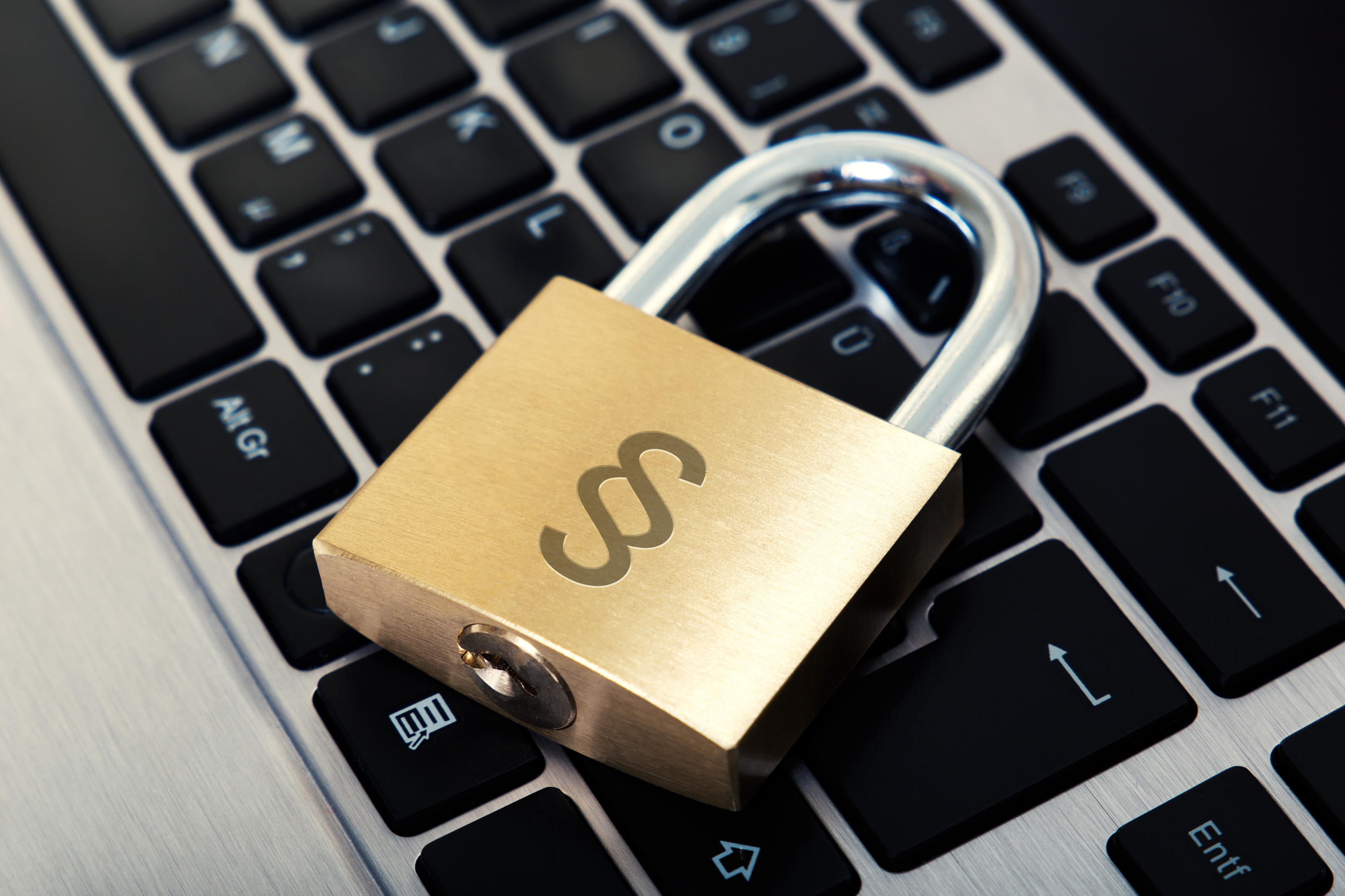 Vorhangschloss mit graviertem Paragraphen-Symbol auf Laptop-Tastatur